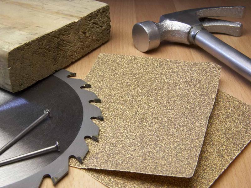 Gros plan sur les outils de préparation et d’application pour la peinture bois et fer extérieur, incluant brosses, ponceuses et pots de peinture